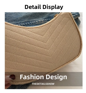 Détail du sac sous le bras en feutre matelassé beige avec zip doré clair et coutures en V