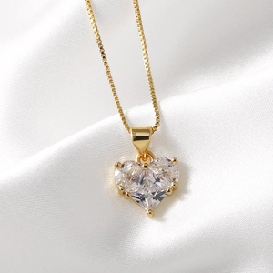 Elegant gold heart pendant necklace with clear cubic zirconia on soft white silk backdrop