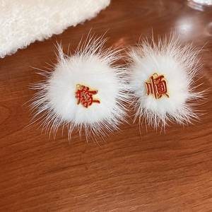 Detailed macro view of white plush pompom earrings with gold and red Chinese character accents