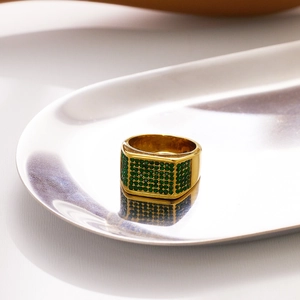Luxurious 18k gold plated men's signet ring with micro-paved green zircons on a silver tray