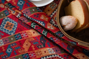Macro detail of red ethnic jacquard tablecloth with thick woven geometric patterns