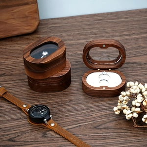 Detail of walnut wood ring box with clear glass lid and soft white velvet lining
