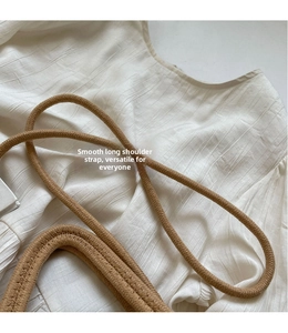Close-up of the smooth woven long shoulder strap on a beige handmade crossbody bag