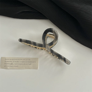 Détail d'une pince à cheveux torsadée en acrylique marbré noir avec des accents dorés chic