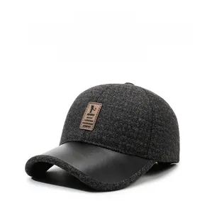 Detail of the warm grey tweed baseball cap with ear flaps and premium black faux leather brim