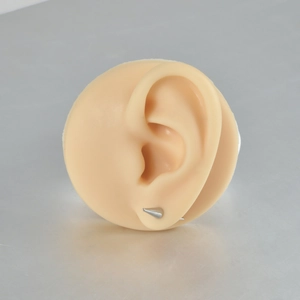 Close-up of a silver cone spike eyebrow piercing on a flesh-colored silicone ear model