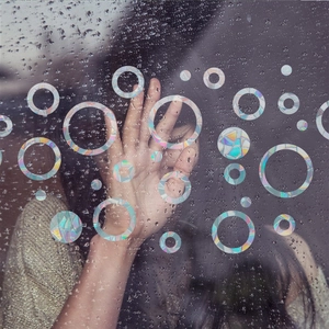 Rainbow prism static cling window film with circular patterns on a rainy window glass