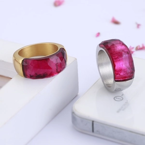 Detail of wide metal rings with rose red faceted resin stones in gold and silver