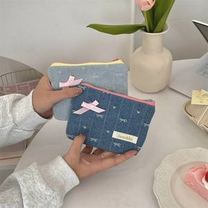Close-up of denim coin purse featuring embroidered white bows and pink ribbon detail