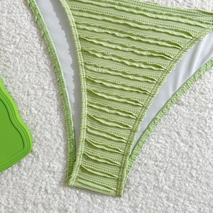 Macro detail of light green crinkled fabric on a bikini bottom with high-quality stitching
