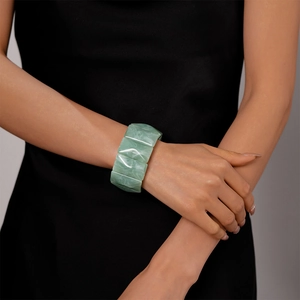 Detail of light green marbled acrylic resin cuff bracelet on a model's wrist