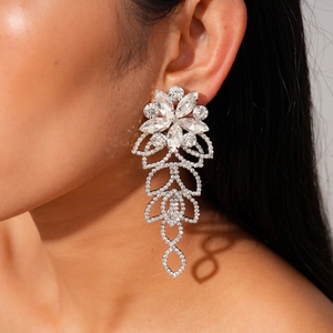 Close-up of sparkling floral leaf tassel earrings with rhinestones on a female model