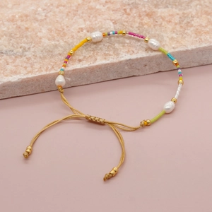 Handmade bracelet with colorful beads and natural freshwater pearls on a stone background