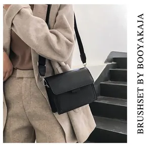 Detail of a minimalist black square crossbody bag with a wide adjustable shoulder strap