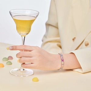 Elegant silver tennis bracelet with multi-colored square-cut gemstones worn by a model