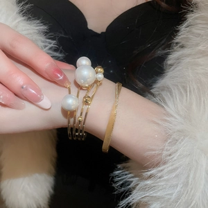 Close-up of gold layered pearl open cuff and diamond bracelet set on a model wrist