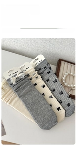 Detail of ballet style knit socks with black bows, white lace trim and grey fabric