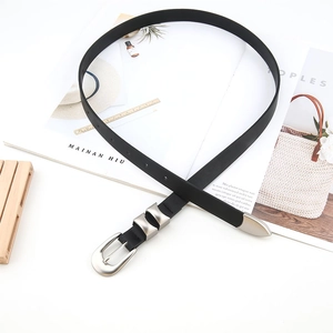 Detail of a thin black leather belt with vintage silver buckle and metal tip accents