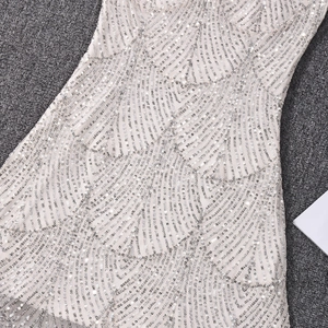 Détail de paillettes argentées sur robe moulante avec motif à vagues et maille