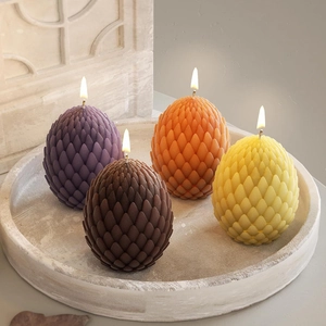 Detalle de cuatro velas de huevo de dragón con textura de escamas en bandeja de piedra