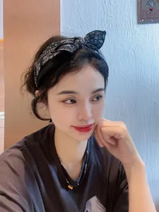 Détail d'un serre-tête en tissu noir à motif cachemire blanc avec nœud papillon