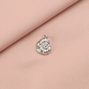 Detailed view of a silver shell-shaped stainless steel pendant on pink fabric background