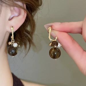 Detail of French vintage gold earrings with amber beads and faux pearls on a model