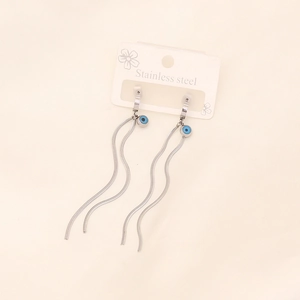 Minimalist stainless steel evil eye tassel earrings on a premium beige textile background