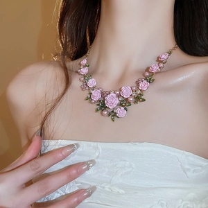 Close-up of pink rose flower necklace with pearls and rhinestones on model neck