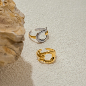 Abstract geometric 18k gold open rings displayed on a textured stone background