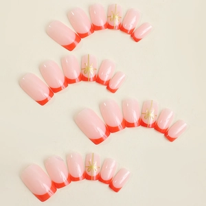 French tip press on nails with red edges and gold bow accents in medium square shape