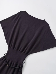 Detail view of knitted dress featuring batwing sleeves and ribbed waist with black belt
