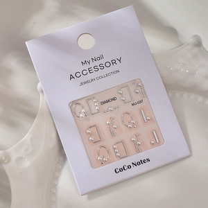 Macro view of 5D pearl nail art stickers with silver geometric frames on a white tray