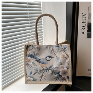 Nahaufnahme von Vogel- und Blumendruck auf strukturierter Jute-Tasche mit Rundgriffen