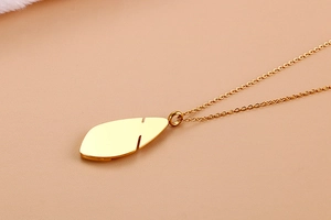 Macro shot of a gold-plated teardrop necklace with hollow design on leather surface