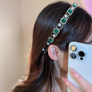 Detail of emerald and pearl headband with gold metal base worn by a model