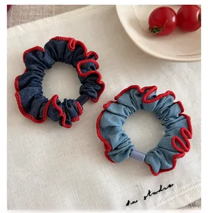 Detail of denim scrunchies with red scalloped edges and plastic accents on fabric