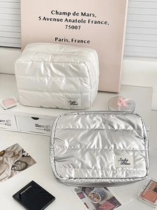 Detailed view of quilted makeup bags in pearl white and silver with metallic finish