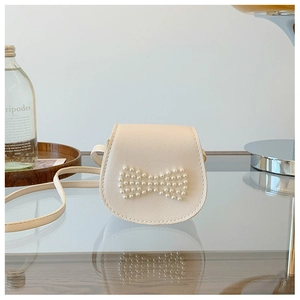 Detail of cream white PU leather girl's purse with pearl bow on glass surface