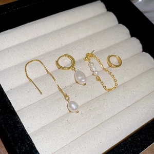 Macro shot of a four-piece freshwater pearl gold earring set on a white velvet jewelry box