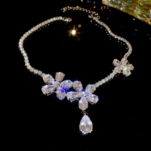 Detailed macro shot of a silver flower necklace with sparkling zircon drop pendants