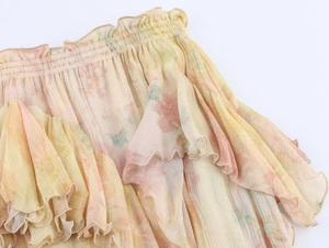 Detailed close-up of floral chiffon fabric with layered ruffles and elastic waistband