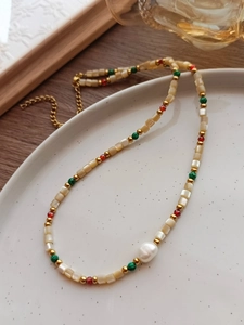 Primer plano del collar de cuentas con perla barroca sobre plato de cerámica y madera