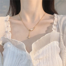 Détail d'un pendentif aile de papillon doré avec une longue chaîne à pompon au cou