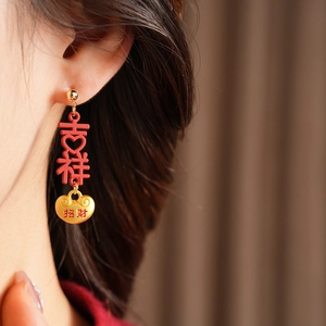 Detail of red and gold Chinese character drop earrings with lucky charm design