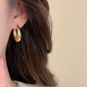 Close-up of minimalist gold teardrop earrings featuring a polished metallic finish on a model