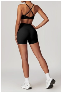 Dettaglio del reggiseno sportivo nero con quattro spalline incrociate e pantaloncini a vita alta