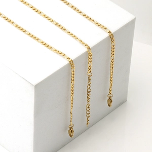 Detailed view of three gold Figaro chain bracelets with lobster clasps on a white base