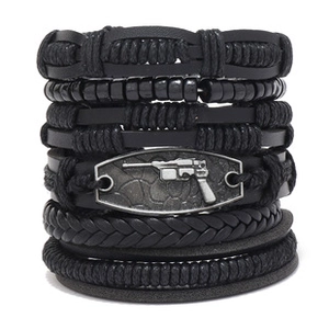 Detail of layered black braided leather bracelets with a square metal pistol charm