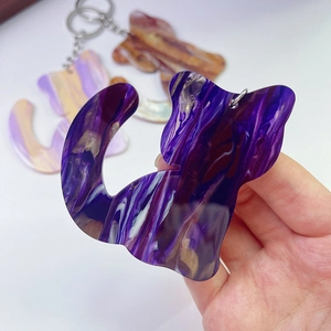 Close-up of purple marble acrylic cat keychain pendant with golden fluid pattern detail